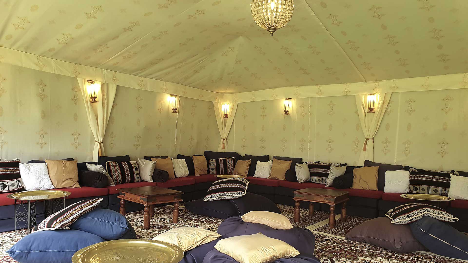 An Arabian tent with cream Jasmine linings with gold Indian print and low level chillout seating.