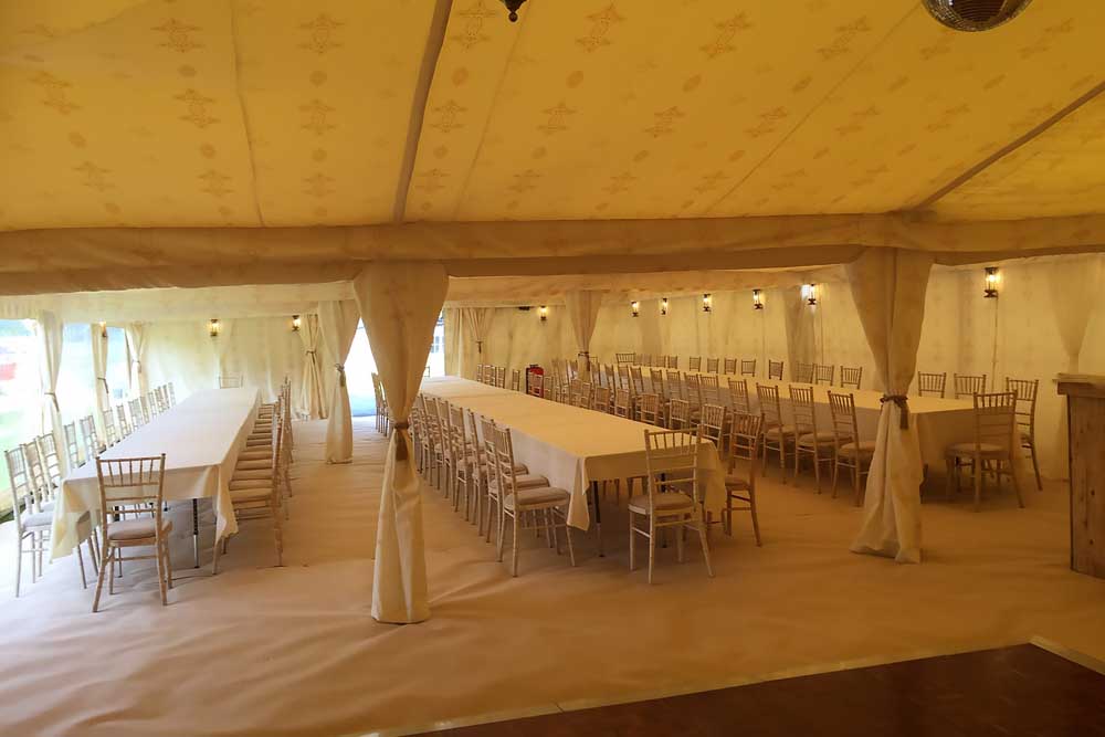 A 9x18m Wedding Marquee with Jasmine Lining, Tables and Chairs and Dancefloor.