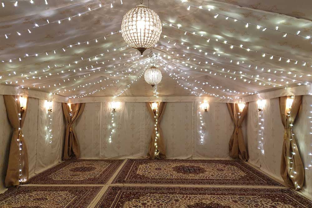 A 9x6m Boutique Tent with Jasmine Lining, Fairy Lights and Cream Persian Carpets.