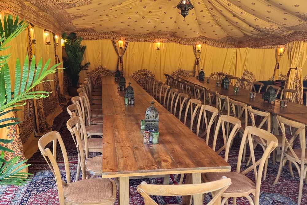 A 6x9m Arabian tent set up for dining with tables and chairs