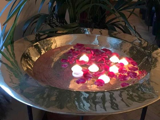 A giant brass dish filling with water rose petals and floating candles.
