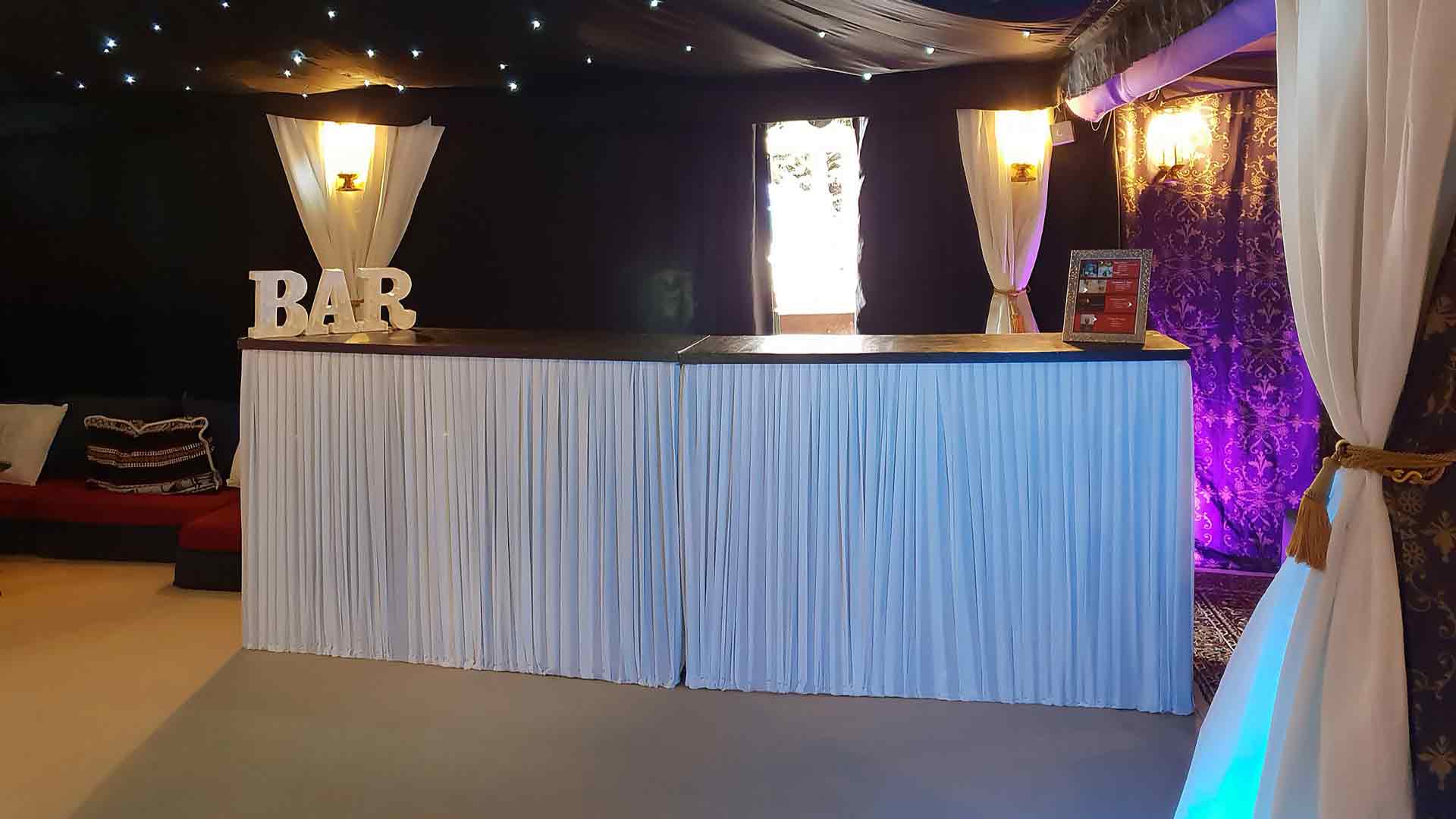 Two Wooden Bar Units Joined Together with a White Pleated Cover, Out on Hire for a 50th Birthday Party