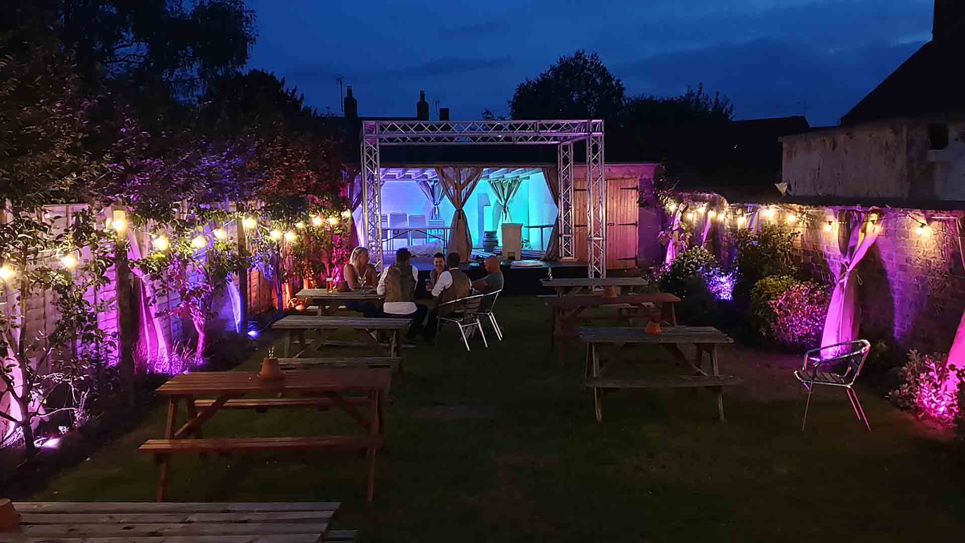 Festoon and Uplighter Lighting Creating a Colorful Ambiance for an Outdoor Wedding